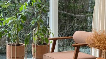 A cozy seating area with a view of a lush garden through large windows.