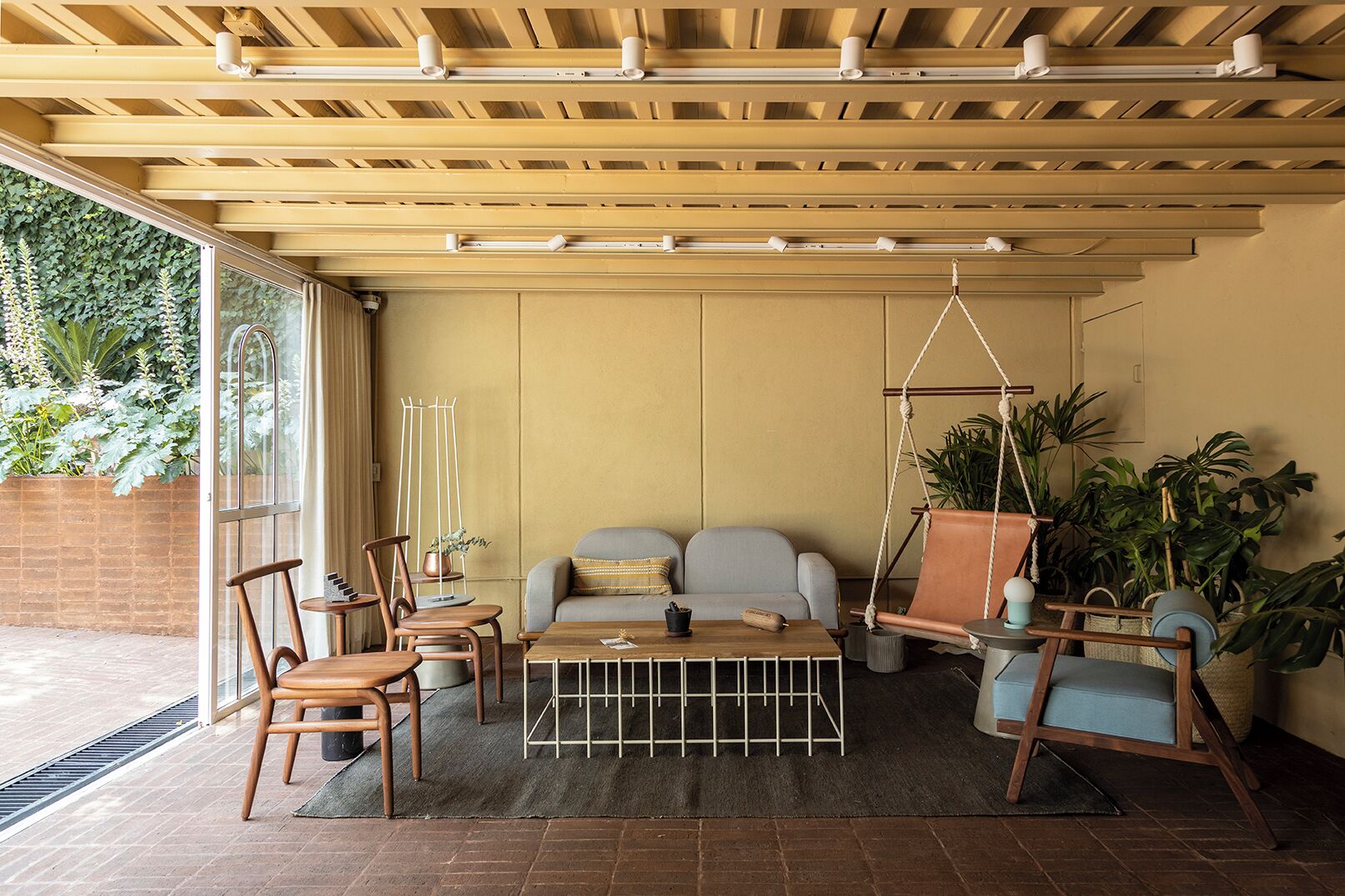 A cozy living room with a sofa, chairs, a coffee table, and a hanging swing.