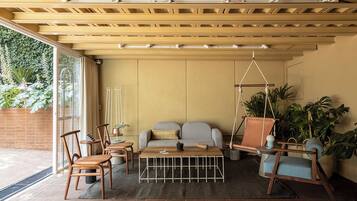A cozy living room with a sofa, chairs, a coffee table, and a hanging swing.