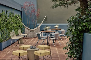 An outdoor seating area with a hammock, round tables, and chairs.