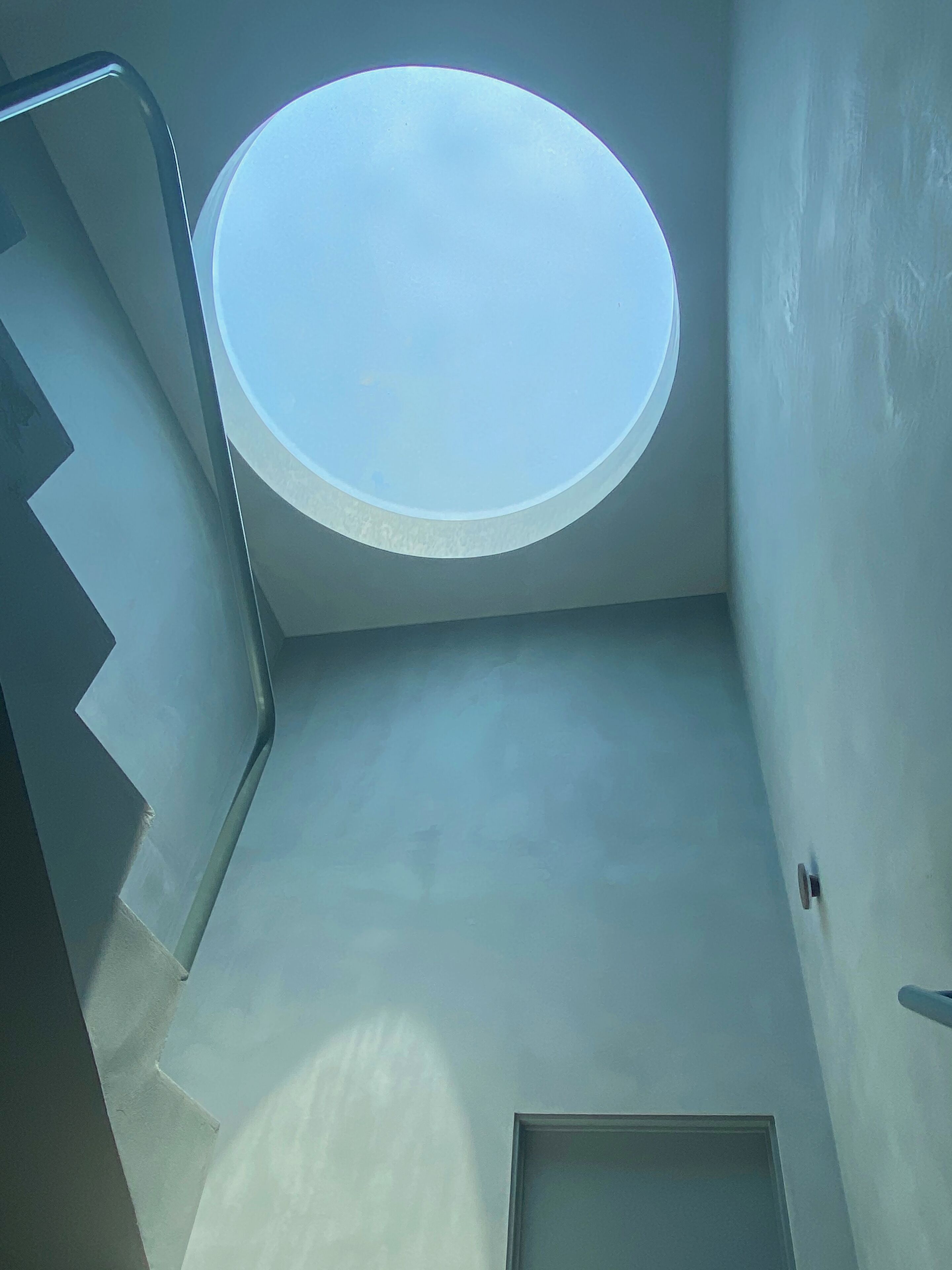 A staircase with a skylight leading to a flat ceiling.