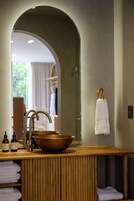A bathroom with a wooden vanity, a copper basin, and a mirror.