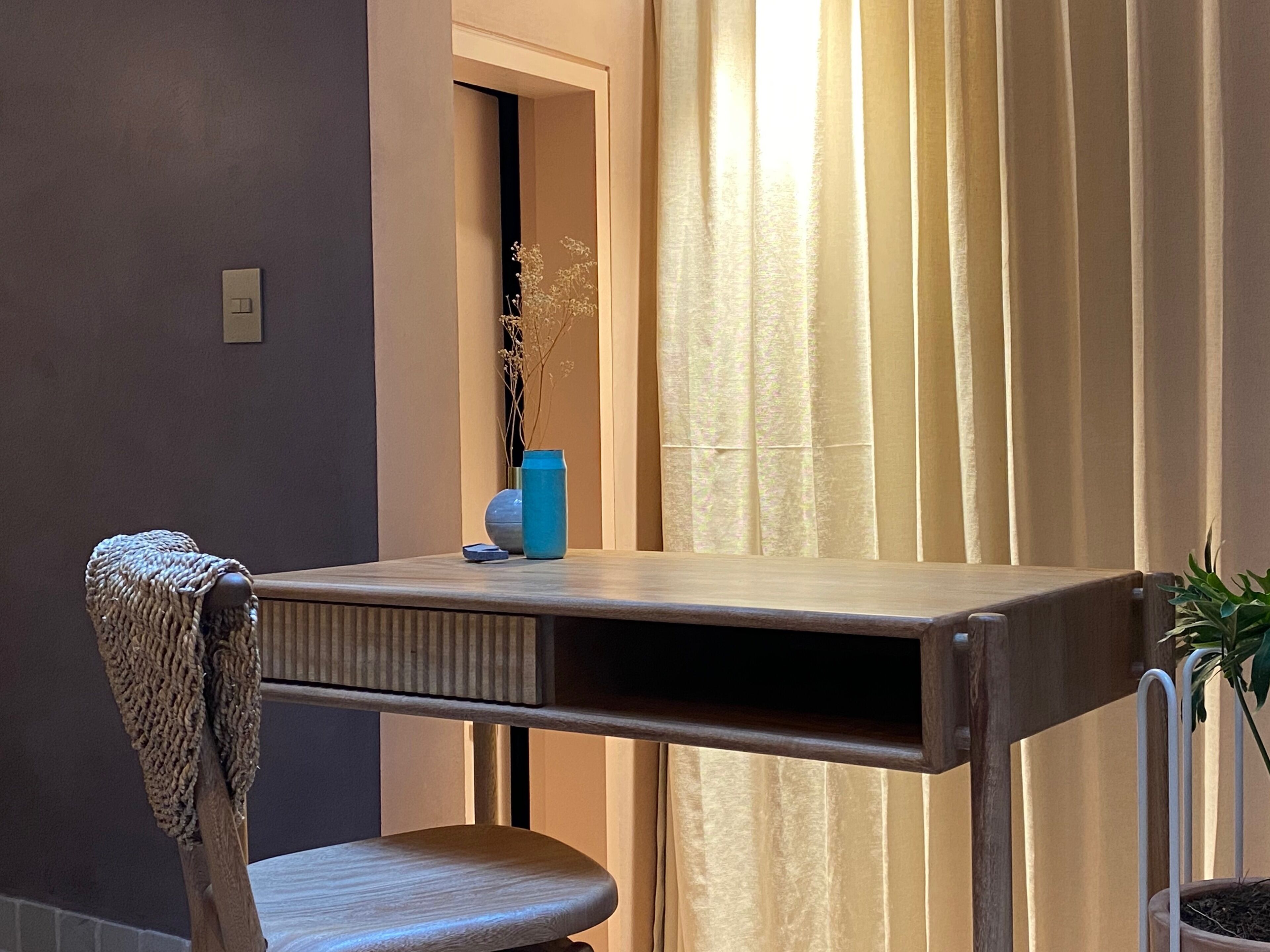 A small, modern room with a wooden table, a chair, and a potted plant.