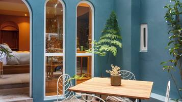 A room with a wooden table and chairs, a potted plant, and a view through a window.