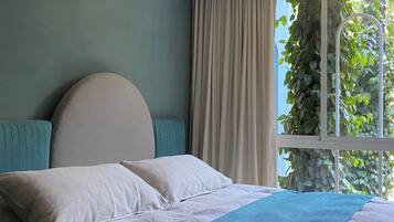 A bedroom with a bed, curtains, and a window with greenery outside.