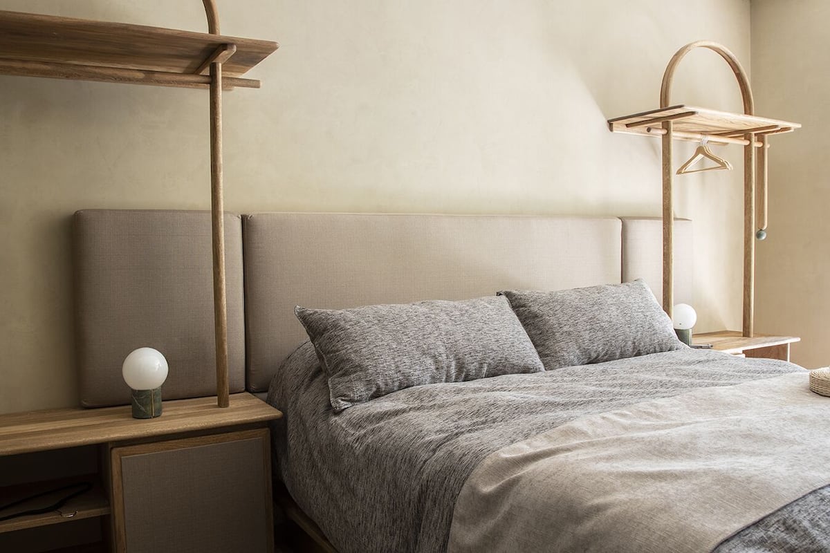 A neatly arranged bedroom with a bed, bedside tables, and a hanging light fixture.