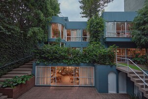 A modern two-story building with a curved facade, large windows, and a balcony.