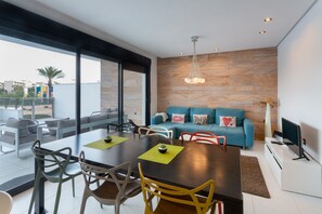 A modern living room with a dining area, a sofa, and a TV.