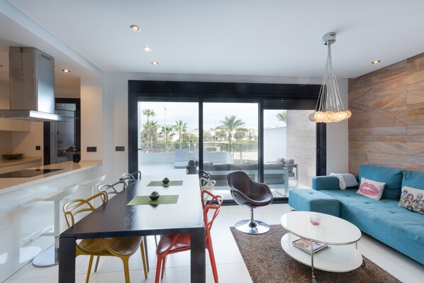 A modern living space with a dining area, a sofa, and a view of the outdoors.