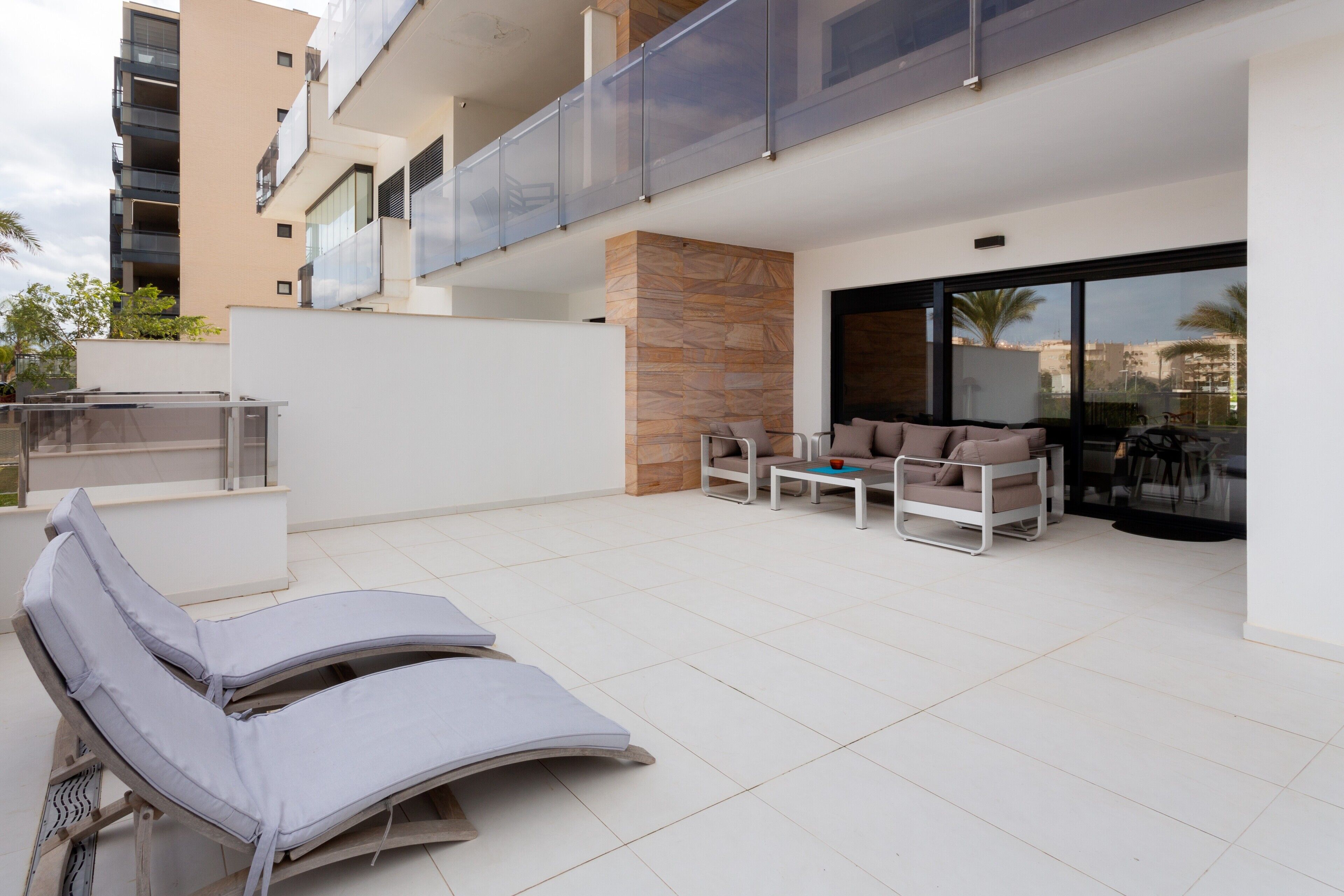 A modern outdoor lounge area with sun loungers, a table, and a seating arrangement.