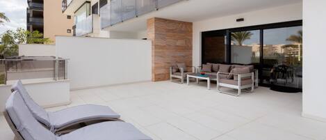 A modern outdoor lounge area with sun loungers, a table, and a seating arrangement.