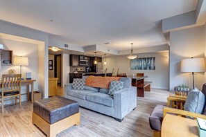 Een moderne woonkamer met een bank, een poef en een eethoek met een tafel en stoelen.