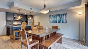 A modern kitchen with dark cabinets, a large wooden dining table, and a hanging light fixture. - 3BR, 1250SQFT, NATURE, HOT TUB, KING BEDS, PETS OK (Dead Man's Flats)