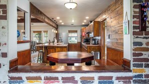 Un'ampia cucina con una grande isola, mobili in legno e una parete decorata con mattoni.