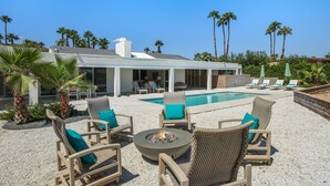 A poolside area with wicker chairs, a fire pit, and a pool. - Casual Elegance in the Desert | A Louisa Davis Property (Rancho Mirage)