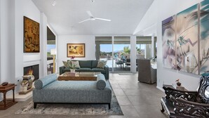 A spacious living room with a large sofa, a fireplace, and artwork on the walls. - Casual Elegance in the Desert | A Louisa Davis Property (Rancho Mirage)