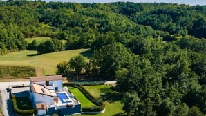 Une maison moderne dotée d’une piscine, entourée d’une végétation luxuriante et située dans un paysage vallonné.