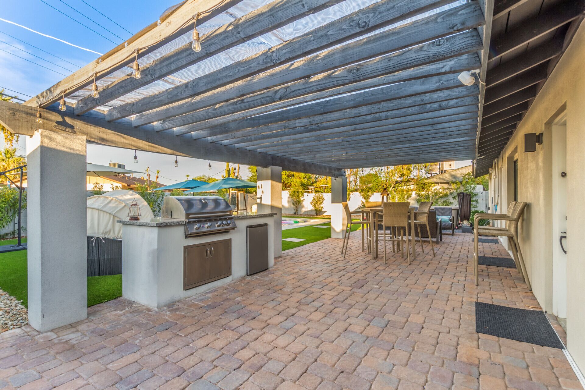An outdoor patio with a grill, seating area, and covered space.