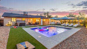 Et moderne hus med swimmingpool, udendørs møbler og en patio.