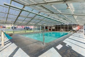 Piscina interna com teto de vidro, um toboágua e área de lazer com espreguiçadeiras.