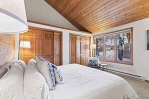 A bedroom with a large bed, wooden wardrobe, and a window with a view of trees. - Abode at Fish Creek, mountain escape, hot tub (Wilson)