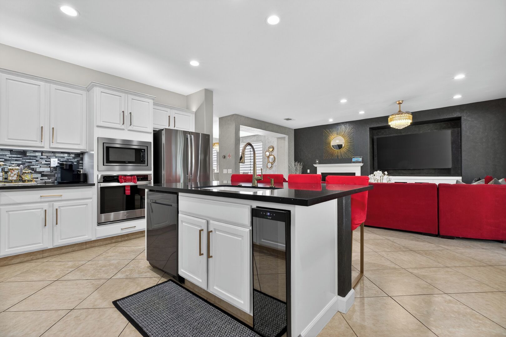 A modern kitchen with white cabinetry, stainless steel appliances, and a red accent sofa in the living area.