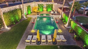 A swimming pool with lounge chairs and umbrellas, surrounded by greenery and a well-lit patio area. - Modern Paradise 15 min 2 Coachella Festival 0.30 acres Lot With misty Huge pool (Indio)