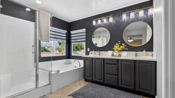 A modern bathroom with a glass-enclosed shower, a freestanding bathtub, and dark cabinetry.