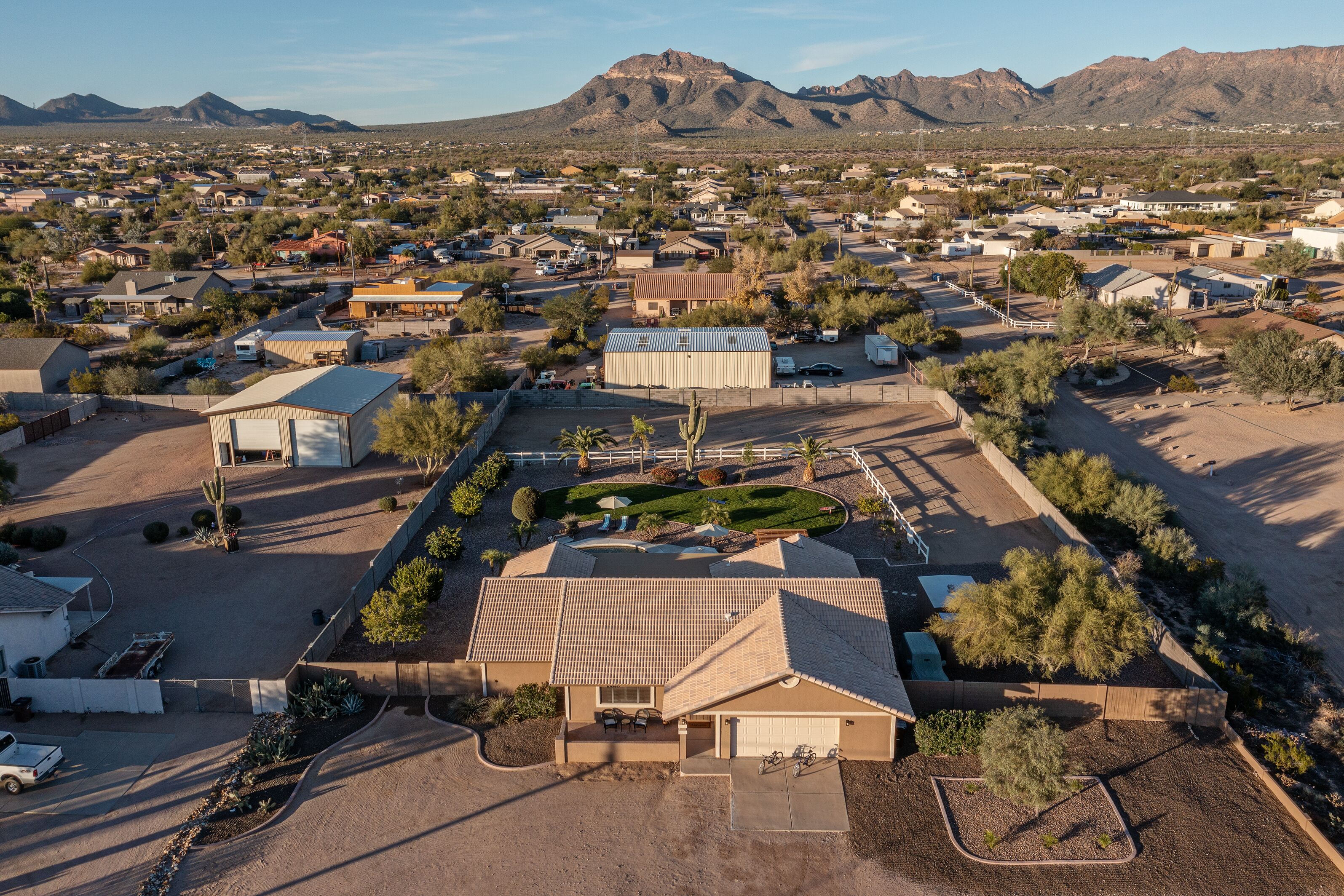 An aerial view of a residential area with houses, a large building, and mountains in the background.