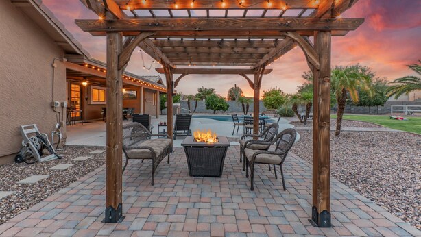 A wooden pergola with string lights, a fire pit, and outdoor seating. - PEACEFUL: One Story, 1 Acre Lot, Htd POOL, Fire Pit, Cornhole, 3 Bikes, TVs All BRs, RV Parking (Mesa)