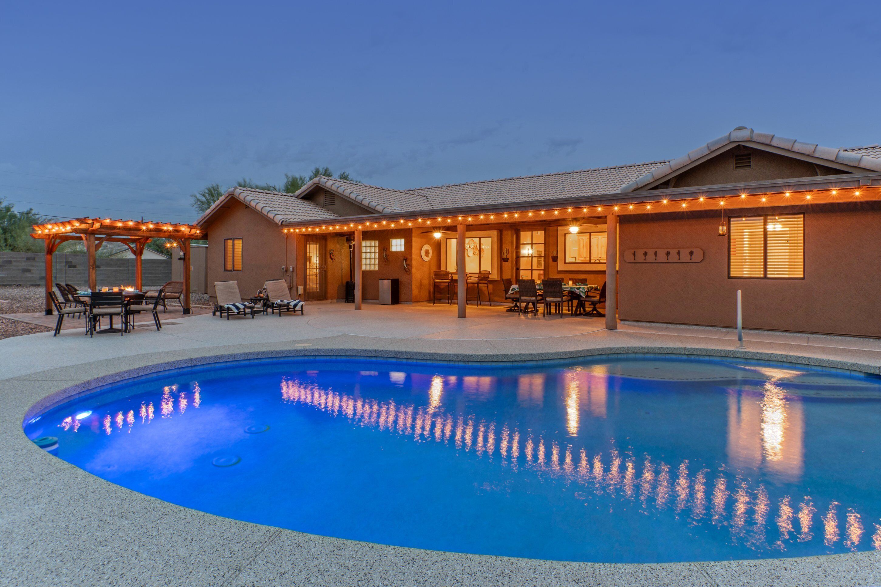 Ett hus med en swimmingpool, utomhusmöbler och ljusslingor.