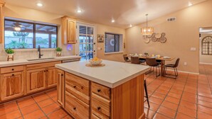 A spacious kitchen with wooden cabinets, a large island, and a dining area with a table and chairs. - PEACEFUL: One Story, 1 Acre Lot, Htd POOL, Fire Pit, Cornhole, 3 Bikes, TVs All BRs, RV Parking (Mesa)