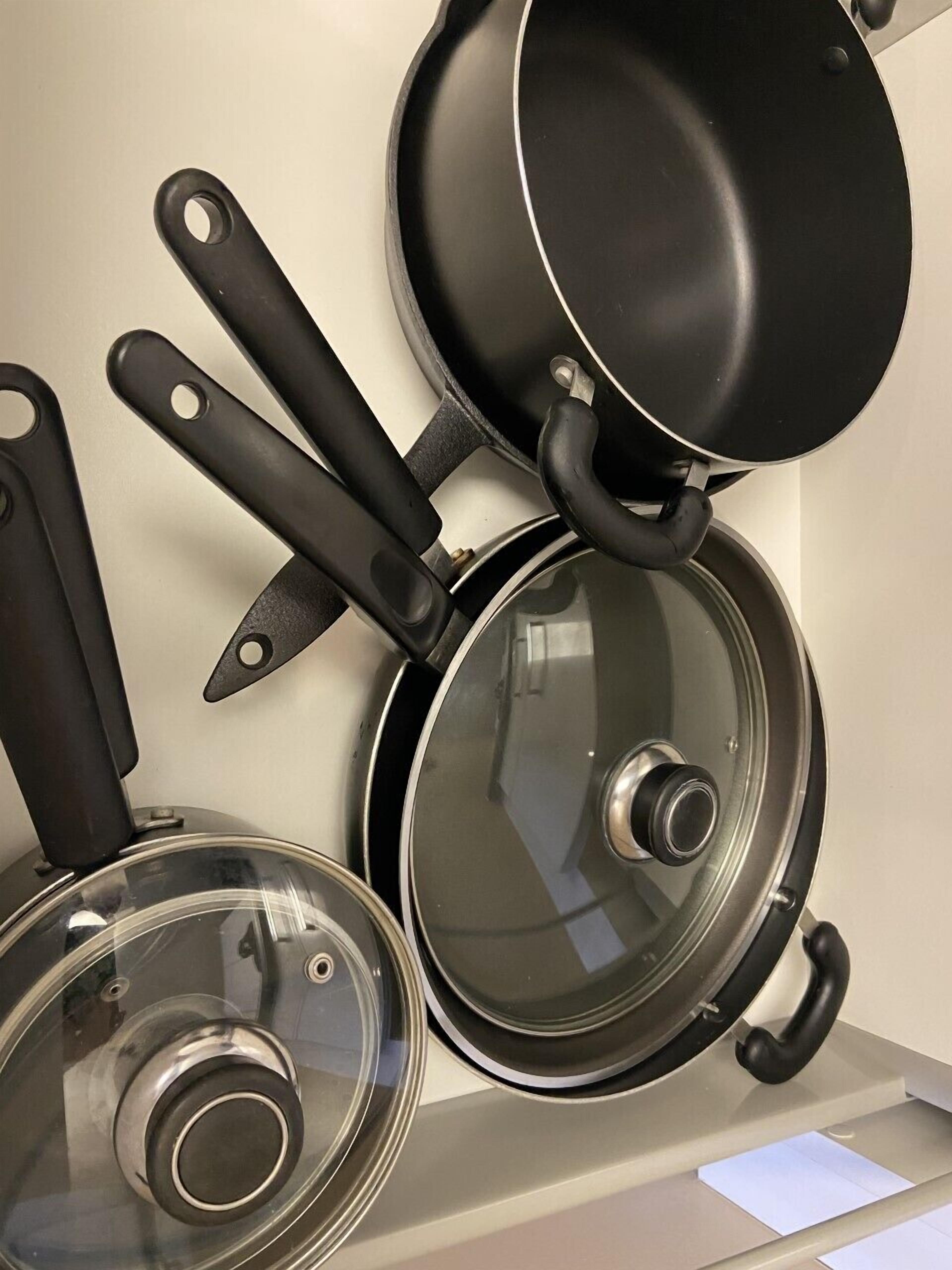 Una cocina con estufa, sartén, olla y tapa.