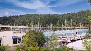 A marina with boats docked, a building labeled "Sealand PHO", and a forested hillside in the background. - This is the life! 2 bedroom oceanfront condo close to everything. (Nanaimo)