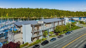 A modern building with a marina in the background. - This is the life! 2 bedroom oceanfront condo close to everything. (Nanaimo)
