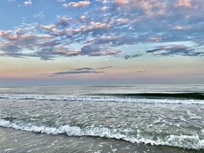 A beach with waves and a sunset sky. - Come and enjoy the beautiful Surfside beach and “heav’n fun” in this cozy home! (Freeport)