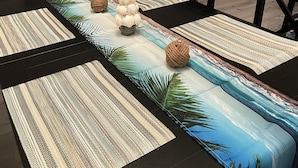 Un coin repas avec une longue table, des chaises noires et un sapin de Noël en arrière-plan.