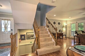 Staircase leads to a cozy upper level with a chair and table below.