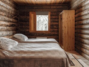 A log cabin bedroom with a bed, a window, and a wardrobe. - Napakymppi by Interhome (Kuusamo)