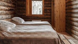 Een slaapkamer in een blokhut met twee bedden, een raam en een kledingkast.