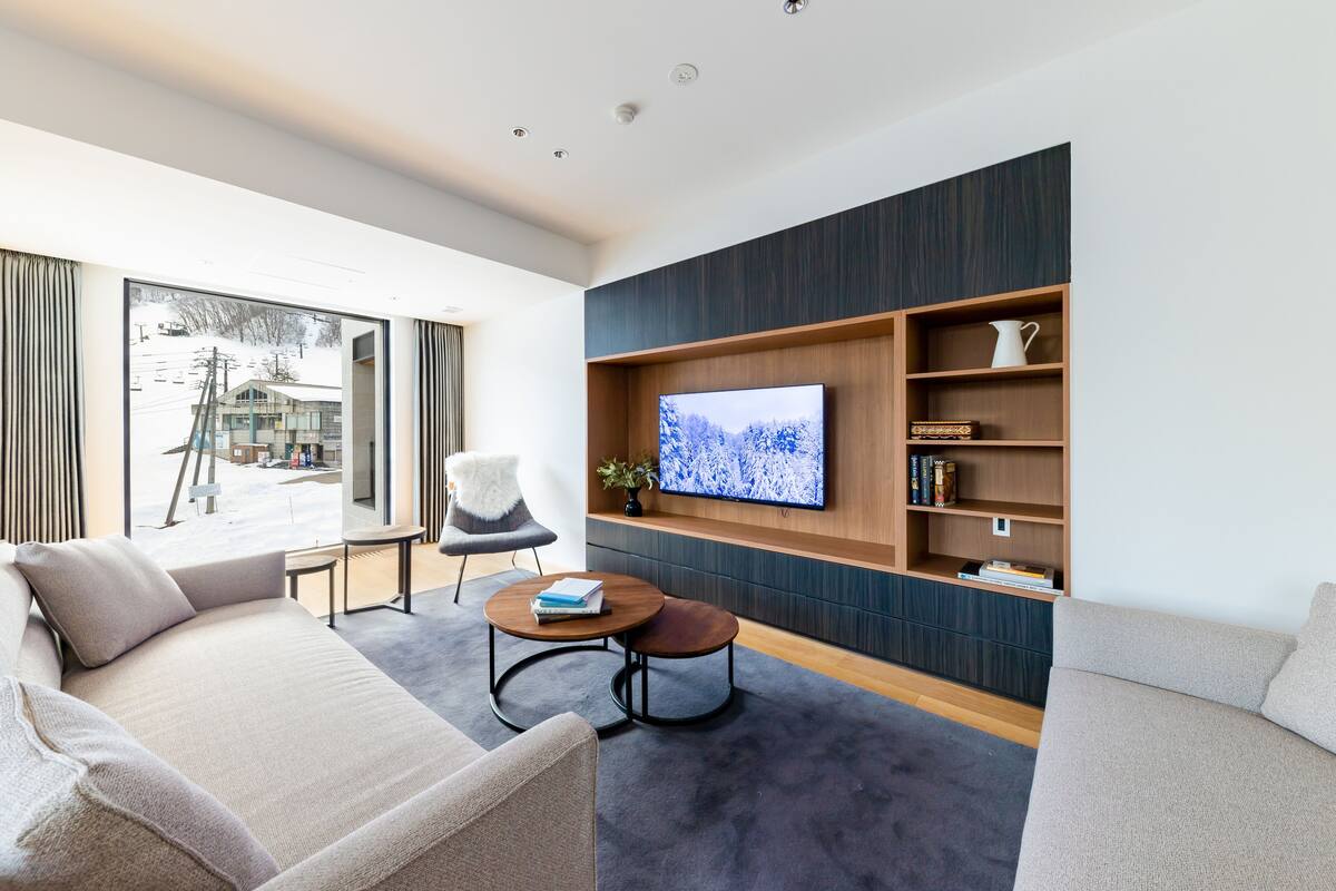 A modern living room with a large TV, a sofa, a chair, and a coffee table.
