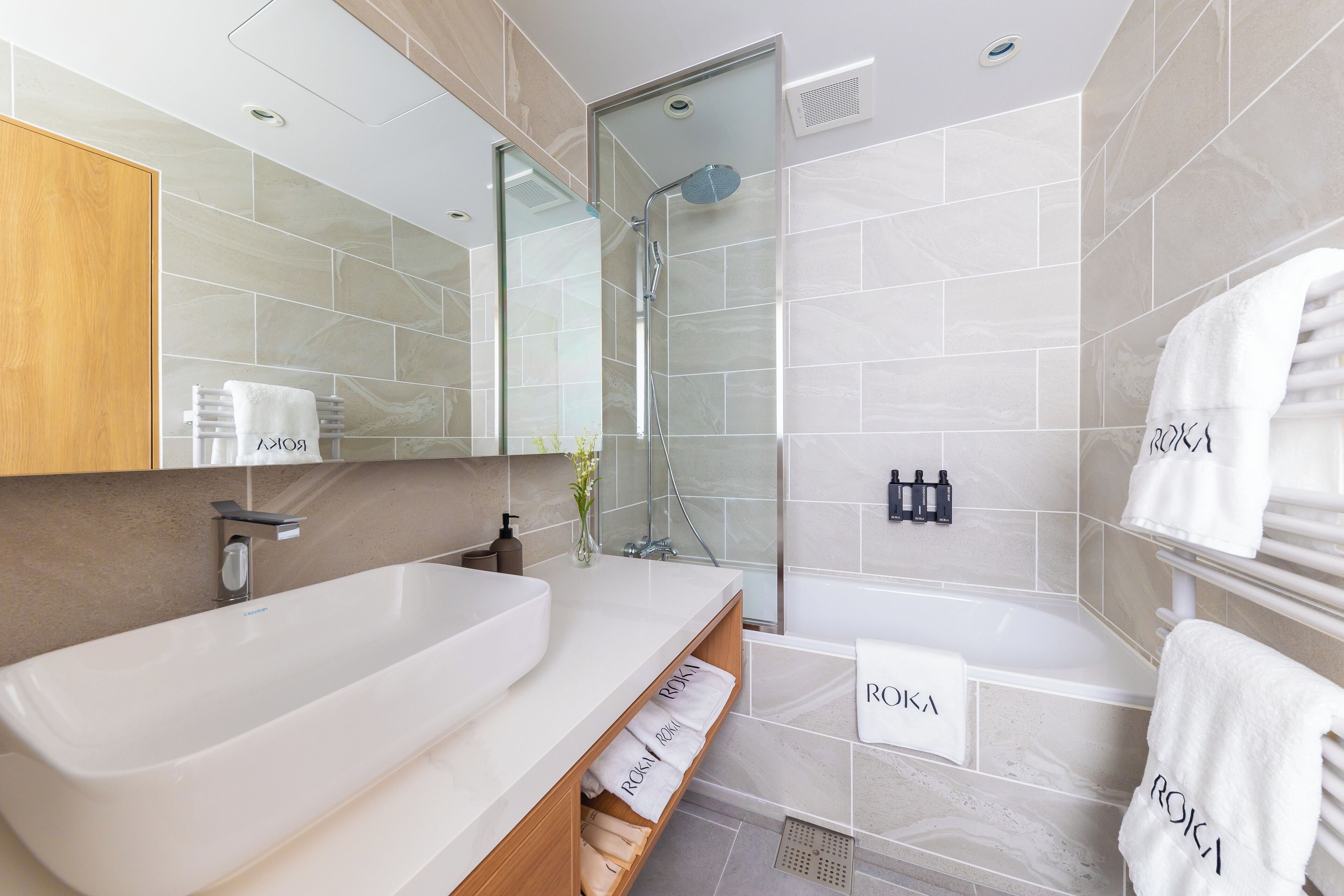 A modern bathroom with a large white sink, a glass-enclosed shower, and a wooden vanity.