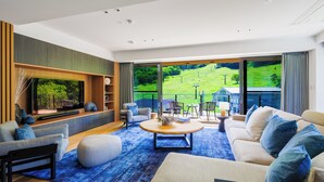Un salon moderne avec une grande fenêtre, un ensemble de canapés, une table basse et une bibliothèque.