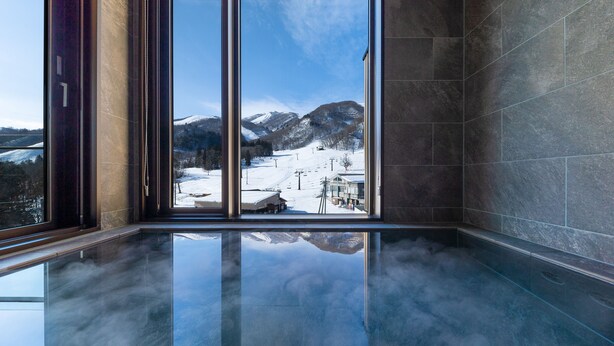 Un intérieur moderne avec une grande baie vitrée donnant sur un paysage montagneux enneigé.
