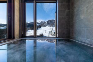 Ein modernes Interieur mit einem großen Fenster, das einen Blick auf eine verschneite Berglandschaft freigibt.