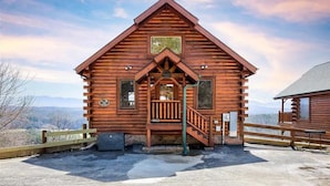 A wooden cabin with a porch, a staircase, and a view of the mountains. - Majestic Smoky Mountains Views | HotTub (Sevierville)