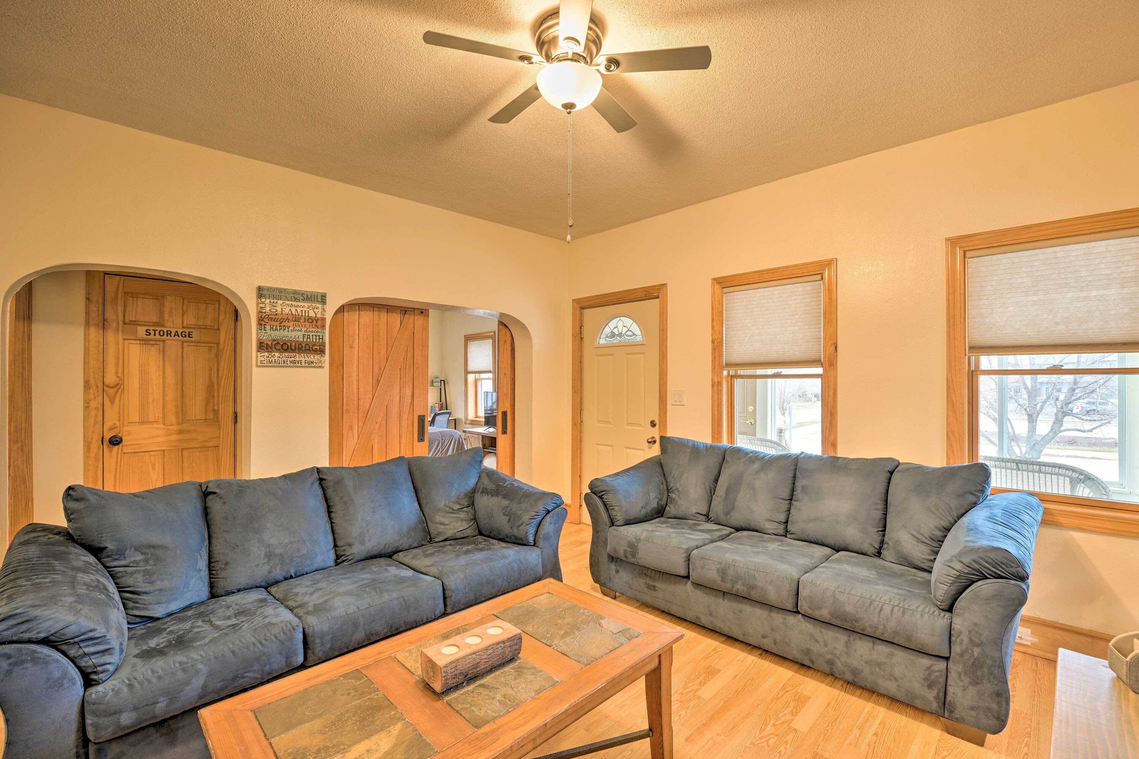 A living room with two dark gray sofas, a wooden coffee table, and a ceiling fan.