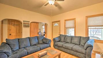 A living room with two dark gray sofas, a wooden coffee table, and a ceiling fan.