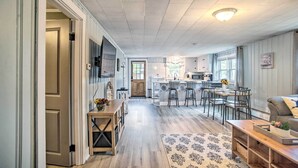 A spacious kitchen with a central island, a dining area with chairs, and a living room with a sofa. - Coastal Comfort Near the Bay! 'Buttermilk Cottage' (Wareham)