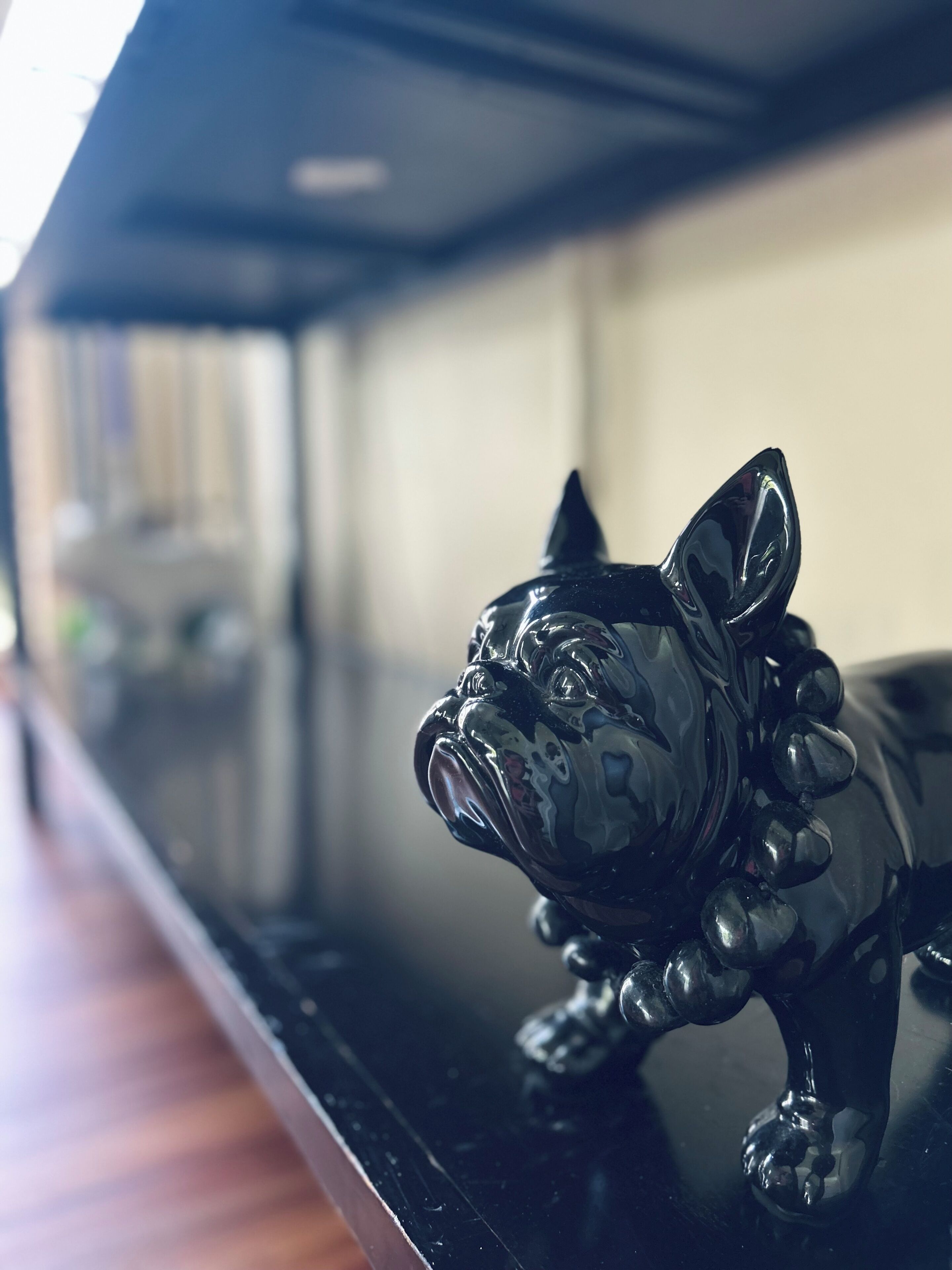 A glossy black figurine of a bulldog on a reflective surface.